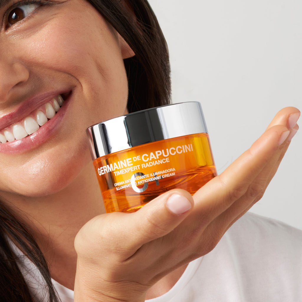 Woman holding a jar of skincare product with a plain background