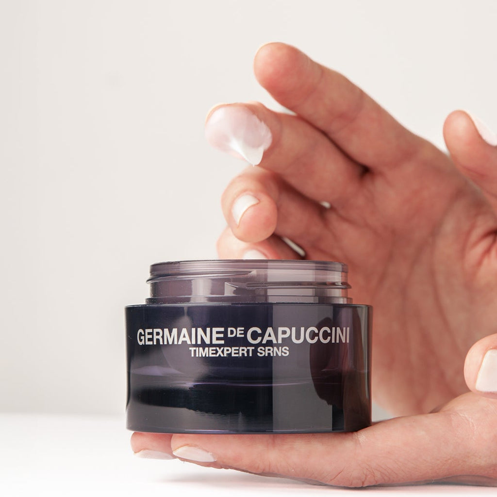 Hand holding a jar of Germaine de Capuccini product against a white background. 