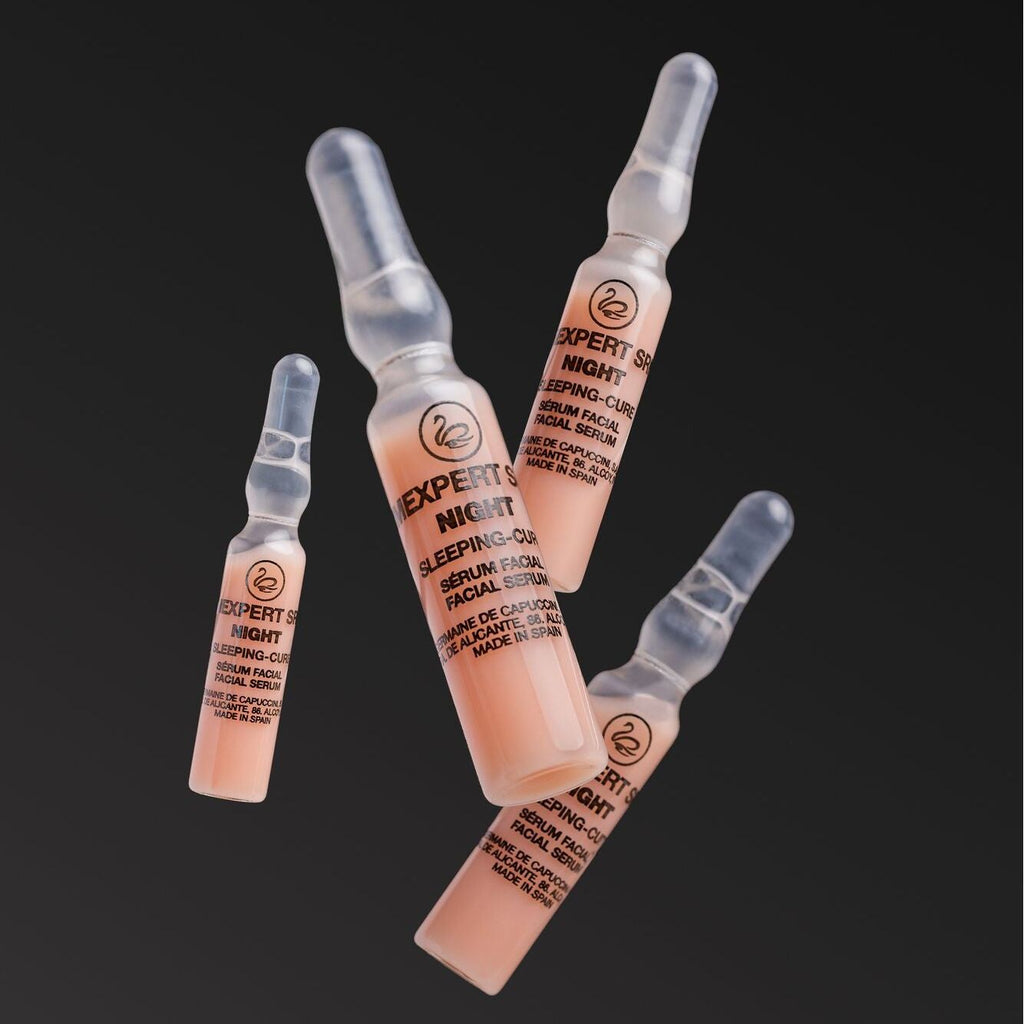 Four skincare ampoules labeled 'Expert Night' on a black background