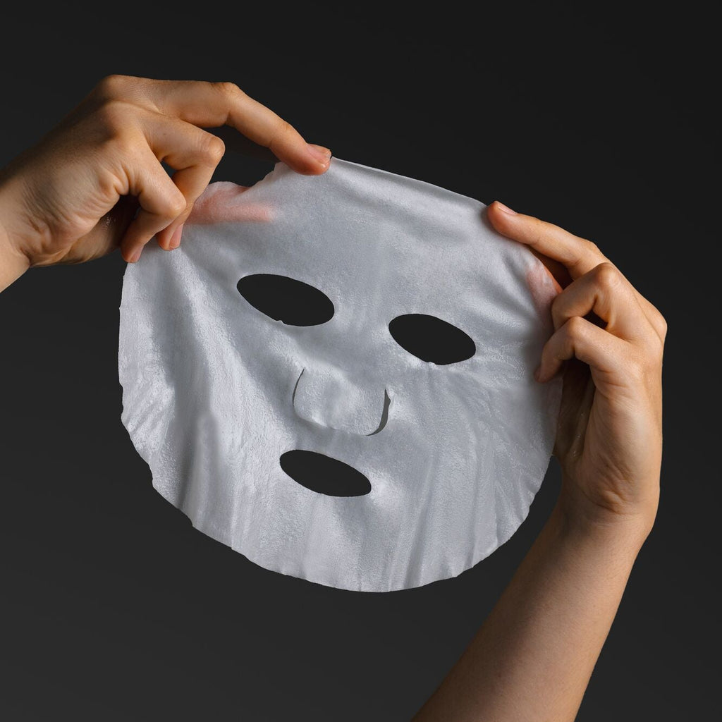 Person holding an anti-ageing face mask with on a dark background