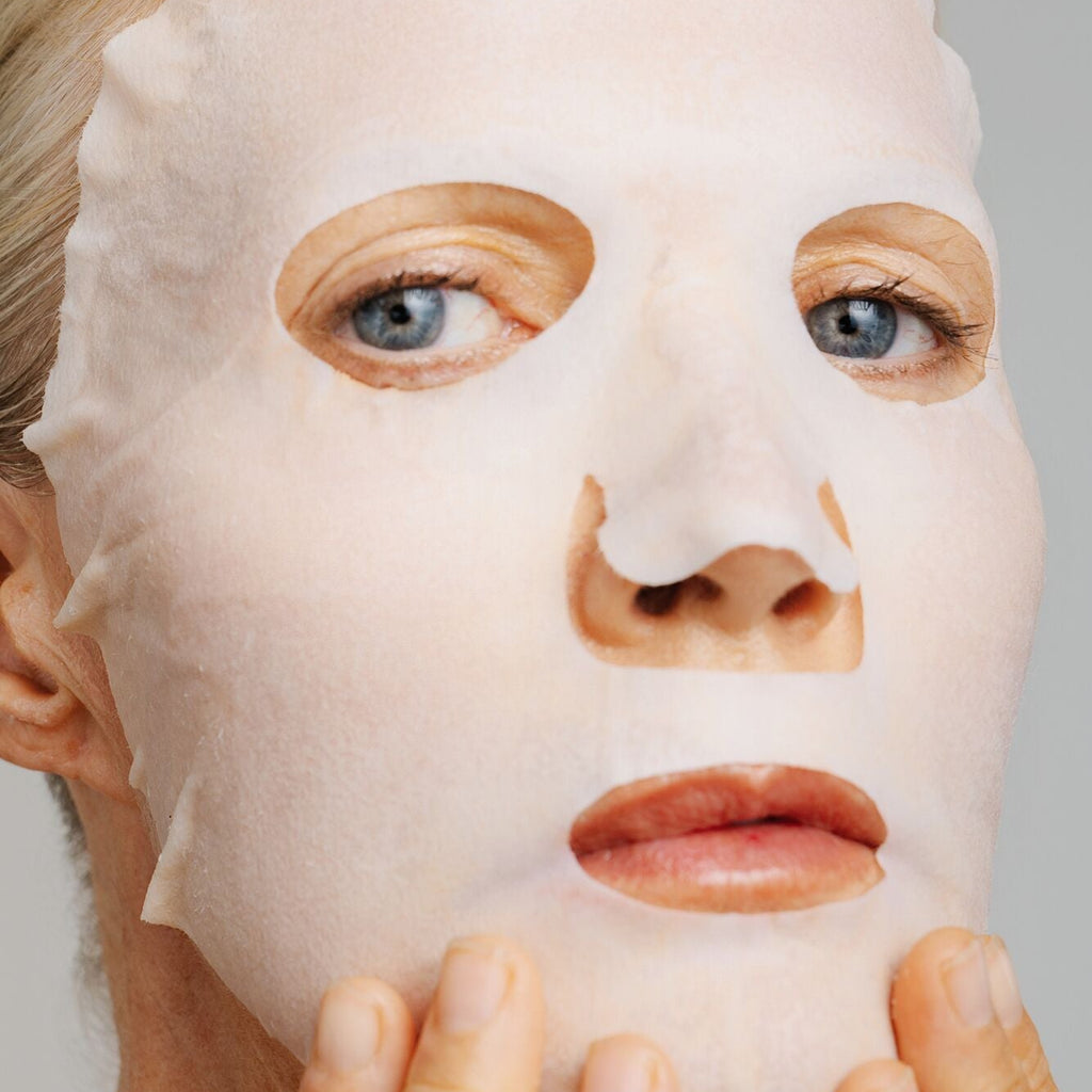 Person wearing a white face mask with a neutral background