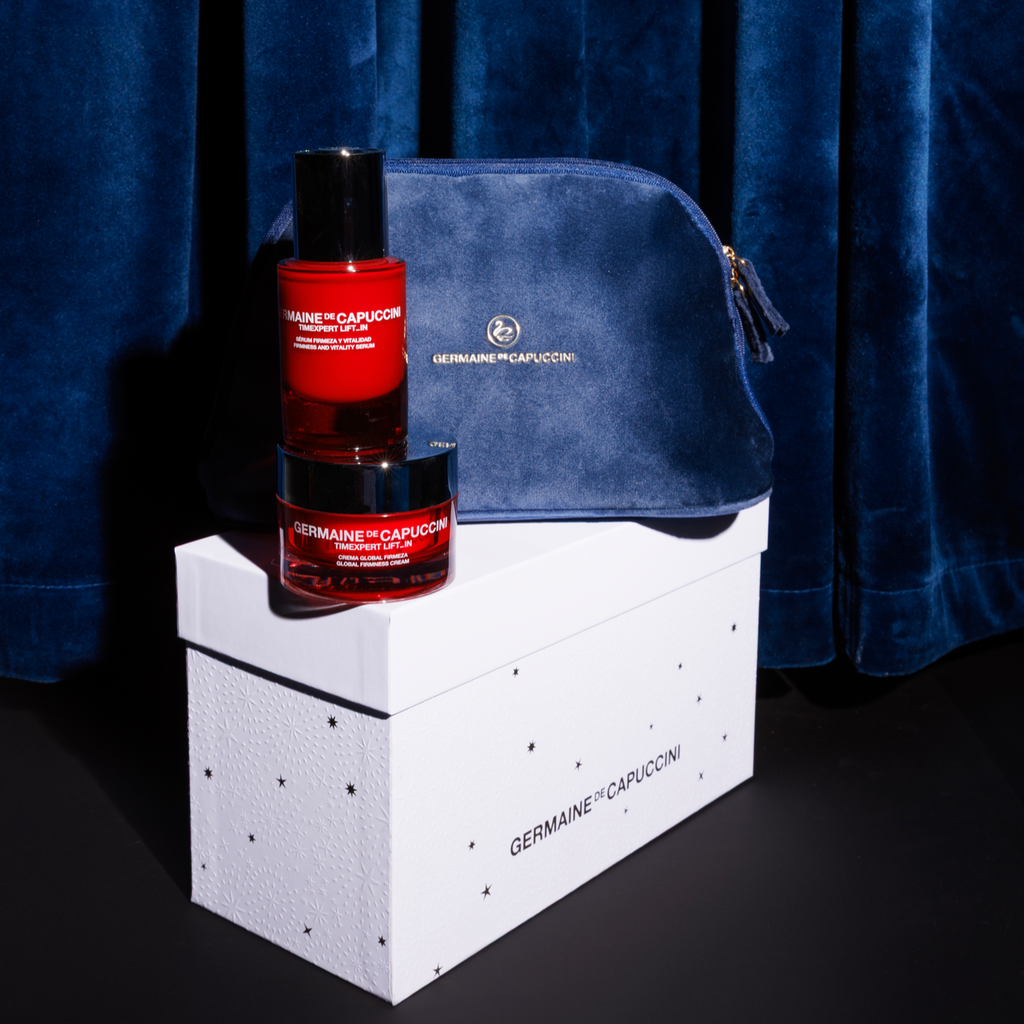 Two bottles of Germaine on a white box with a blue velvet bag against a dark blue curtain.