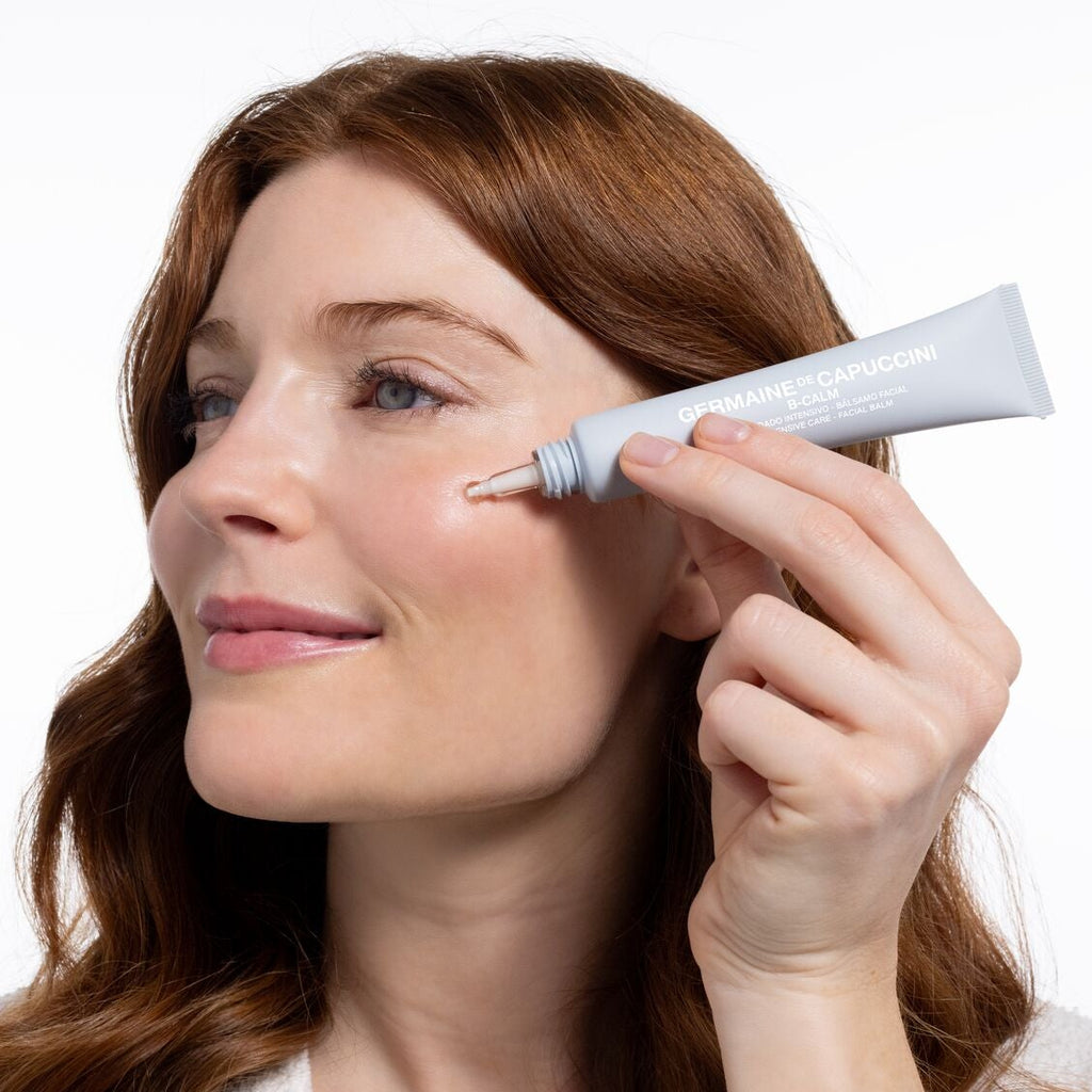 Woman applying cream to her face with a white background